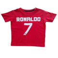 A red short-sleeve t-shirt with 'RONALDO' and the number '7' printed in white on the front, laid flat on a light-colored wooden table.