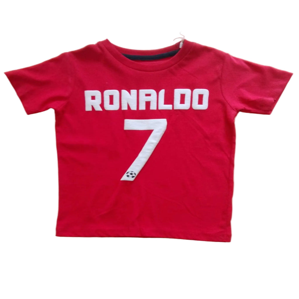 A red short-sleeve t-shirt with 'RONALDO' and the number '7' printed in white on the front, laid flat on a light-colored wooden table.
