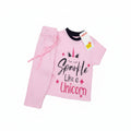 A pink children's two-piece outfit consisting of a short-sleeve top and matching pants, laid flat on a light wood surface. The top features a unicorn graphic with the text 'Unicorn Like a Spewf*ck' in stylized lettering.