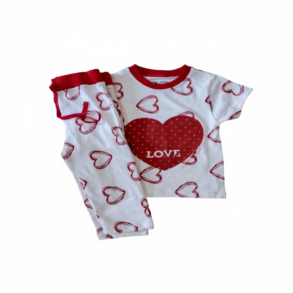 A two-piece baby pajama set consisting of a white short-sleeve top and matching pants, both decorated with red heart patterns. The top features a large red heart on the chest with the word 'LOVE' printed in white, and the pants have a red elastic waistband.