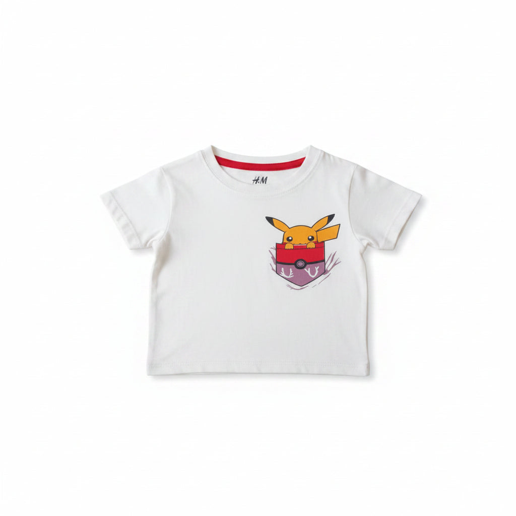 A white short-sleeve kids' t-shirt featuring a Pikachu graphic on a Pokémon bag, laid flat on a light wood surface.