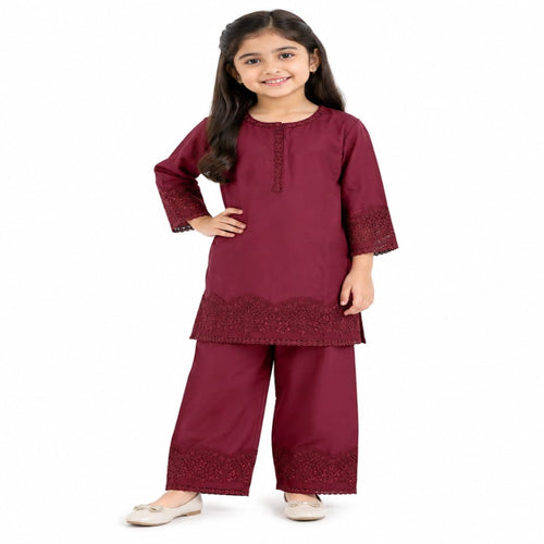 A young girl modeling a three-piece maroon kurta set with matching wide-leg trousers and embroidered lace details, photographed against a solid white background.